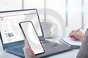 Mockup cellphone. Woman hand holding mobile phone with blank screen in modern office. hand holding smartphone with white screen in