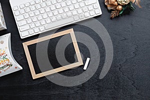 Mockup chalkboard with blank empty screen, new year gift box with Xmas christmas ornaments on black wood home office desk, top