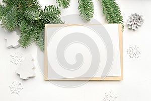 Mockup Christmas greeting card with envelope on wooden white background with fir tree branches and happy new year