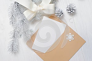 Mockup Christmas greeting card letter in envelope with white tree and cone, flatlay on a wooden background, with place photo