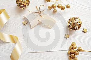 Mockup Christmas greeting card top view and gold ball, flatlay on a white wooden background with a ribbon, with place