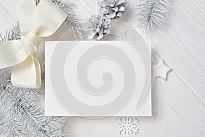 Mockup Christmas greeting card with white tree and cone, flatlay on a white wooden background, with place for your text