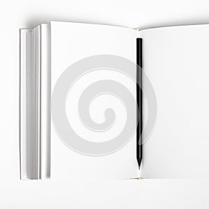 Mockup of closed blank square book and black pencil at white textured paper background