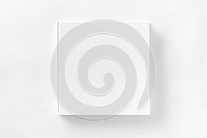 Mockup of closed blank square book at white textured paper