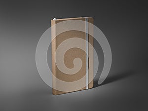 Mockup of a closed craft notebook, standing on a darkened background, with a white elastic band, a bookmark