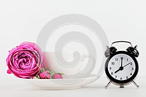 Mockup of coffee cup with rose flower and alarm clock on white desk with clean space for text and design your blogging.