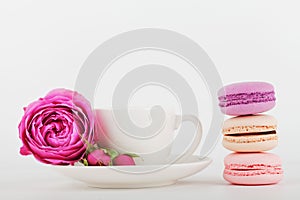 Mockup of coffee cup with rose flower and stack of macaroon on white table with empty space for text and design your blogging.