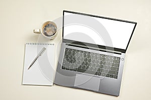 Mockup computer laptop with white blank screen, notepad, coffee cup and copy space on white background