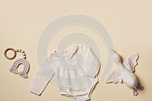 Mockup of cream infant bodysuit made of organic cotton with eco friendly baby accessories, knitted rainbow, soft duck on