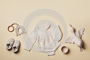 Mockup of cream infant bodysuit made of organic cotton with eco friendly baby accessories, knitted rainbow, soft duck on