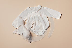 Mockup of cream infant bodysuit made of organic cotton with eco friendly baby accessories, soft duck on beige