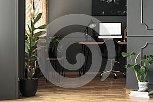 Mockup on desktop computer next to lamp in grey freelancer`s roo