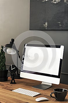 Mockup of desktop computer on wooden desk with lamp in dark home