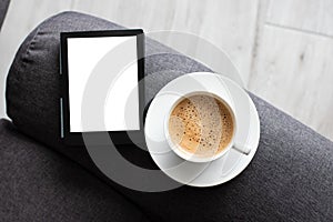 Mockup Ebook on modern armchair With Blank White Screen, to replace your design and Coffee for cozy atmosphere reading