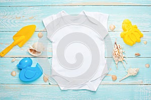 Mockup Flat Lay white baby bodysuit shirt on a blue rustic wood background with a nautical theme,seashells and the sea and