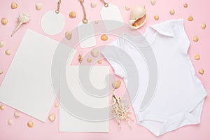 Mockup Flat Lay white baby shirt bodysuit mock-up paper and tags for design on a pink background with a nautical theme, shells and