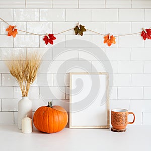 Mockup frame with pumpkin, candle, coffee cup, vase of wheat in cozy home interior with autumn fall decorations. Thanksgiving,