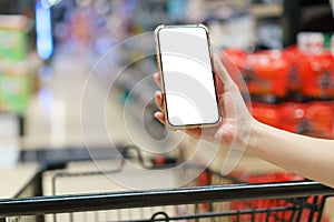 Mockup, hands holding blank white screen mobile phone with shopping cart in supermarket, digital payment concept