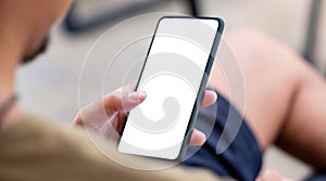 Mockup image blank white screen cell phone.men hand holding texting using mobile on desk at home office