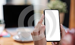 Mockup image blank white screen cell phone.women hand holding texting using mobile on desk at home office