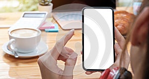 Mockup image blank white screen cell phone.women hand holding texting using mobile on desk at home office