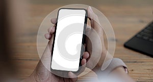 Mockup image blank white screen cell phone.women hand holding texting using mobile on desk at home office