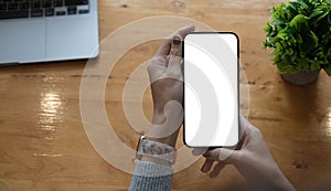 Mockup image blank white screen cell phone.women hand holding texting using mobile on desk at home office