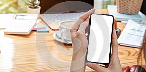 Mockup image blank white screen cell phone.women hand holding texting using mobile on desk at home office