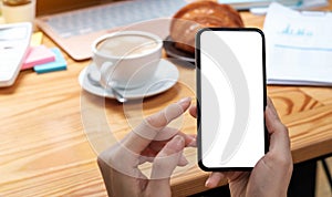 Mockup image blank white screen cell phone.women hand holding texting using mobile on desk at home office