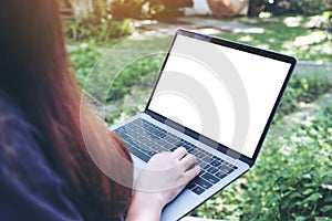 Mockup image of business woman using and typing on laptop with blank white desktop screen , sitting at outdoor with nature