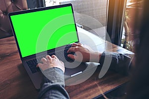 Mockup image of business woman using and typing on laptop with blank white screen and coffee cup on table