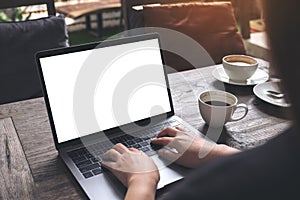 Mockup image of business woman using and typing on laptop with blank white screen and coffee cups