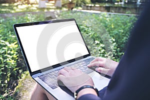 Mockup image of business woman using and typing on laptop with blank white screen , sitting at outdoor