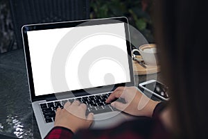 Mockup image of business woman using and typing on laptop with blank white screen , smart phone and coffee cups