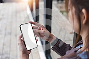 Mockup image of closeup woman hand holding mobile phone with blank white smartphone screen at the outdoor.