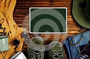 Mockup Image of Digital Tablet. surrounded by Camping Stuff and Cloth. Planning for Travel Outdoors. Flat Lay