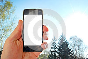 Mockup image of hand holding black mobile phone with blank white screen and green tree forest , nature background