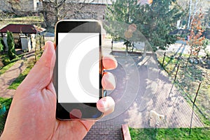 Mockup image of hand holding black mobile phone with blank white screen and green tree forest , nature background