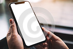 Mockup image of hands holding black mobile phone with blank desktop screen