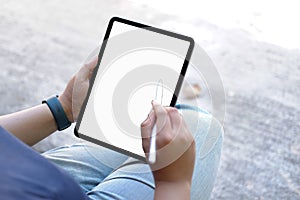 Mockup image of hands holding white mobile phone with blank black desktop screen and a coffee cup on desk