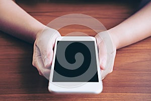 Mockup image of hands holding white mobile phone with blank black screen with hot coffee cup