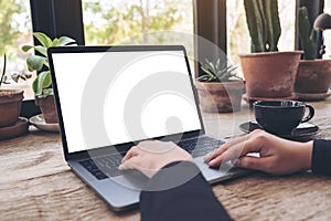 Mockup image of hands using and typing on laptop with blank white desktop screen on vintage wooden table