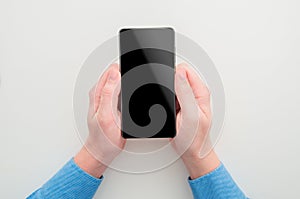 Mockup image of a man with blue shirt holding black mobile phone with blank screen on white background