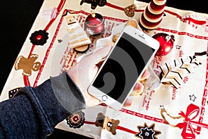 Mockup image of a man`s hand holding black mobile phone with black screen with christmas background