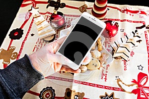 Mockup image of a man`s hand holding black mobile phone with black screen with christmas background