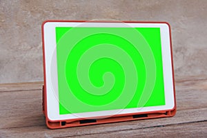Mockup image of  White tablet pc with blank green desktop screen on wooden table