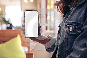 Mockup image of a woman holding and showing black mobile phone with blank white screen