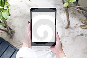 Mockup image of a woman`s hand holding black tablet pc with blank white desktop screen with sand and beach