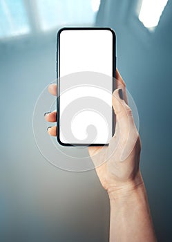 Mockup image of woman`s hand holding thin bezels mobile phone with blank screen in glossy and blurry corporate environment - Imag