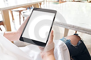 Mockup image of a woman sitting cross legged and holding black tablet pc with blank white desktop screen